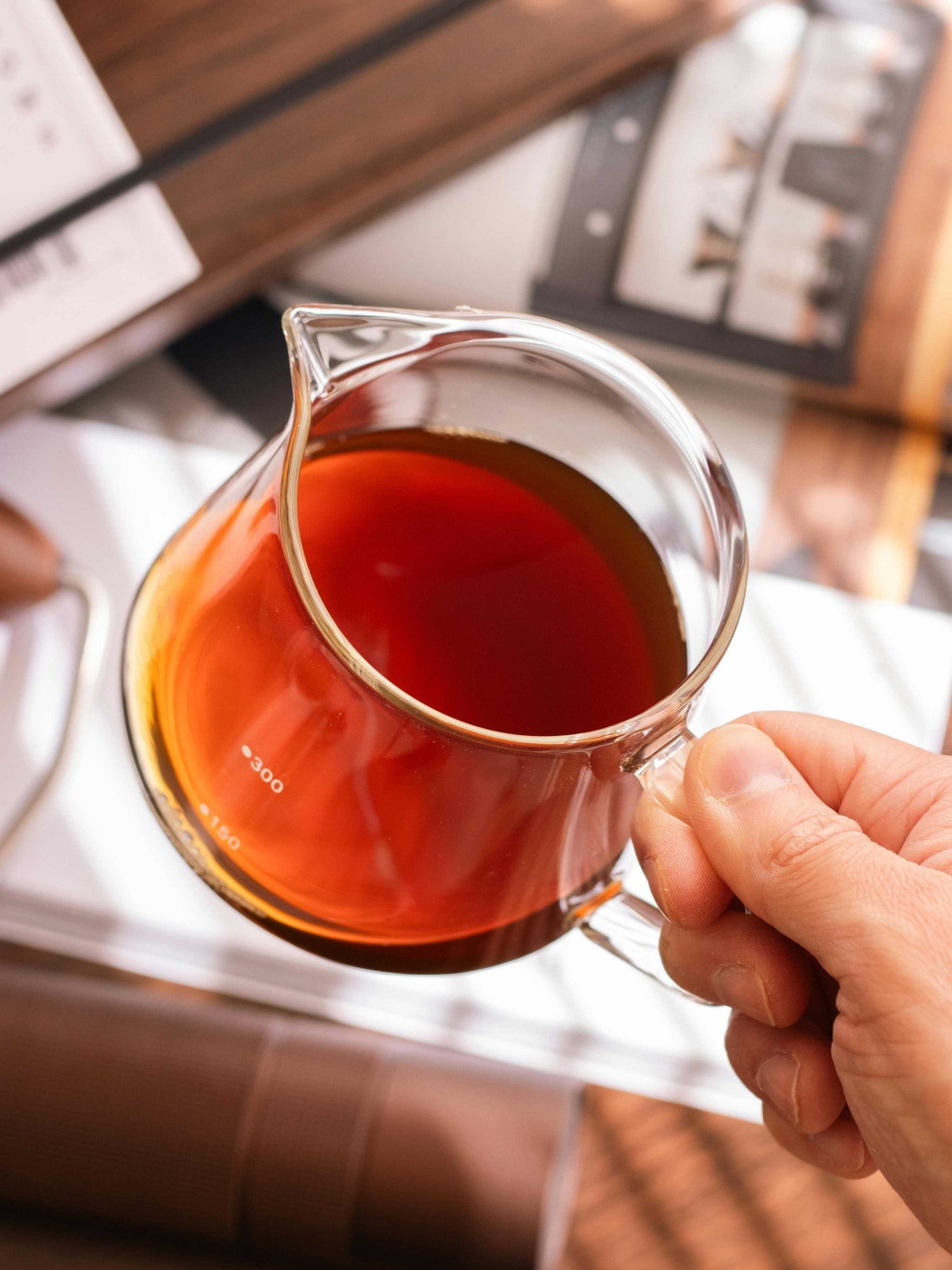 Hand holding glass server with fresh-brewed specialty Honduran coffee, artisan pour-over style.